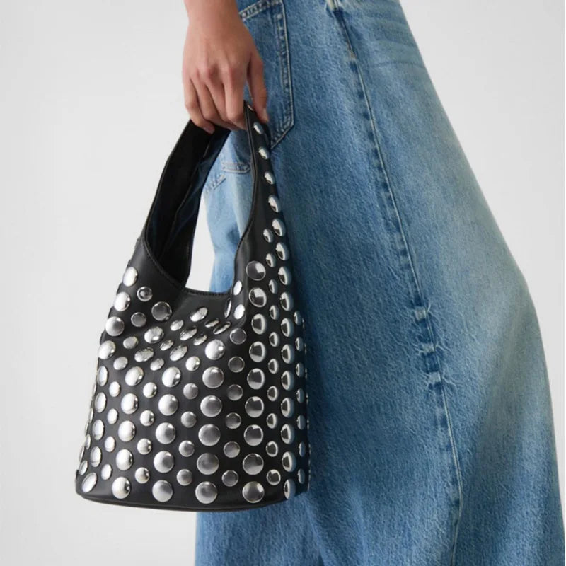 Apportez une touche de sophistication à votre style avec notre sac seau à rivets. Chic, pratique et tendance, il s’adapte à toutes vos occasions avec élégance.