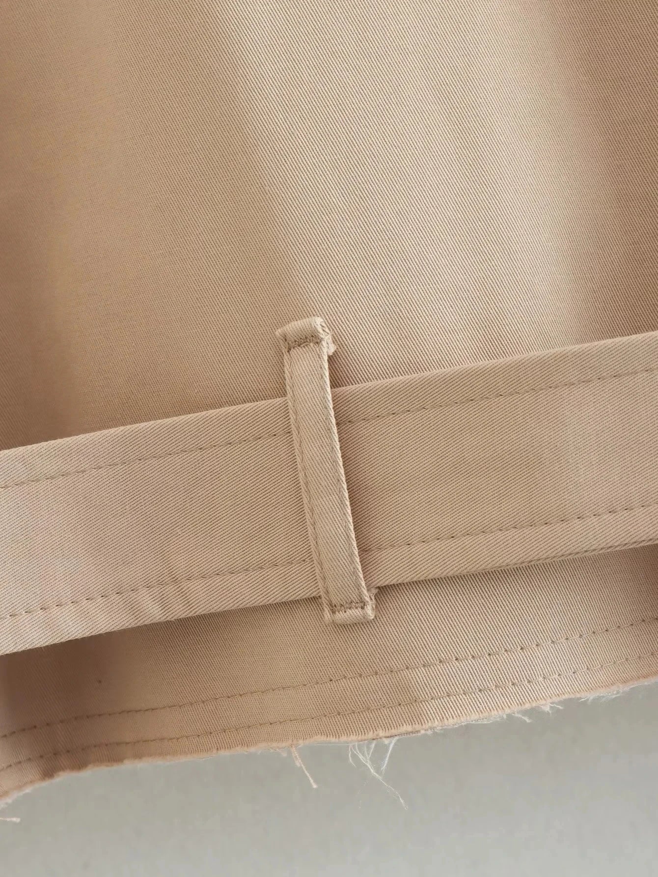 Trench court beige avec ceinture à la taille, look chic et intemporel.