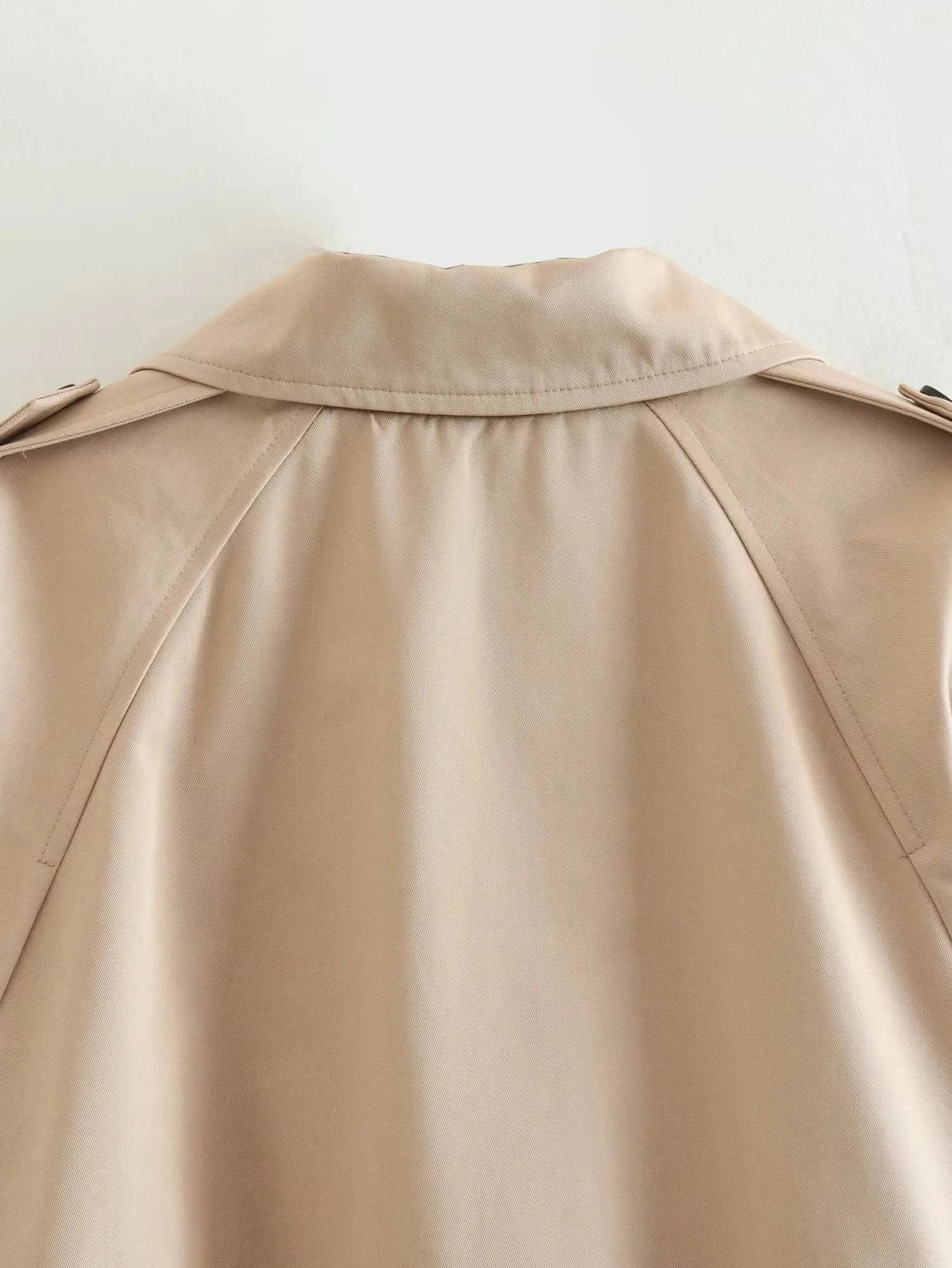 Trench court beige avec ceinture à la taille, look chic et intemporel.