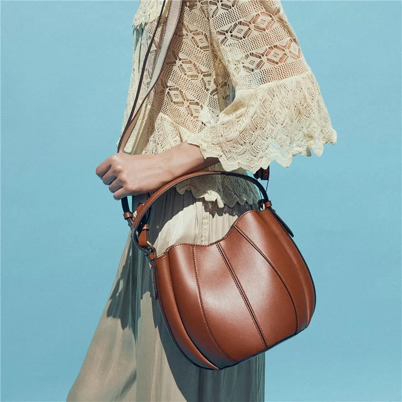 Sac curve en simili cuir marron, forme arrondie avec anse courte élégante.