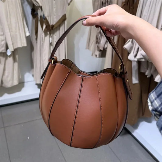 Sac curve en simili cuir marron, forme arrondie avec anse courte élégante.