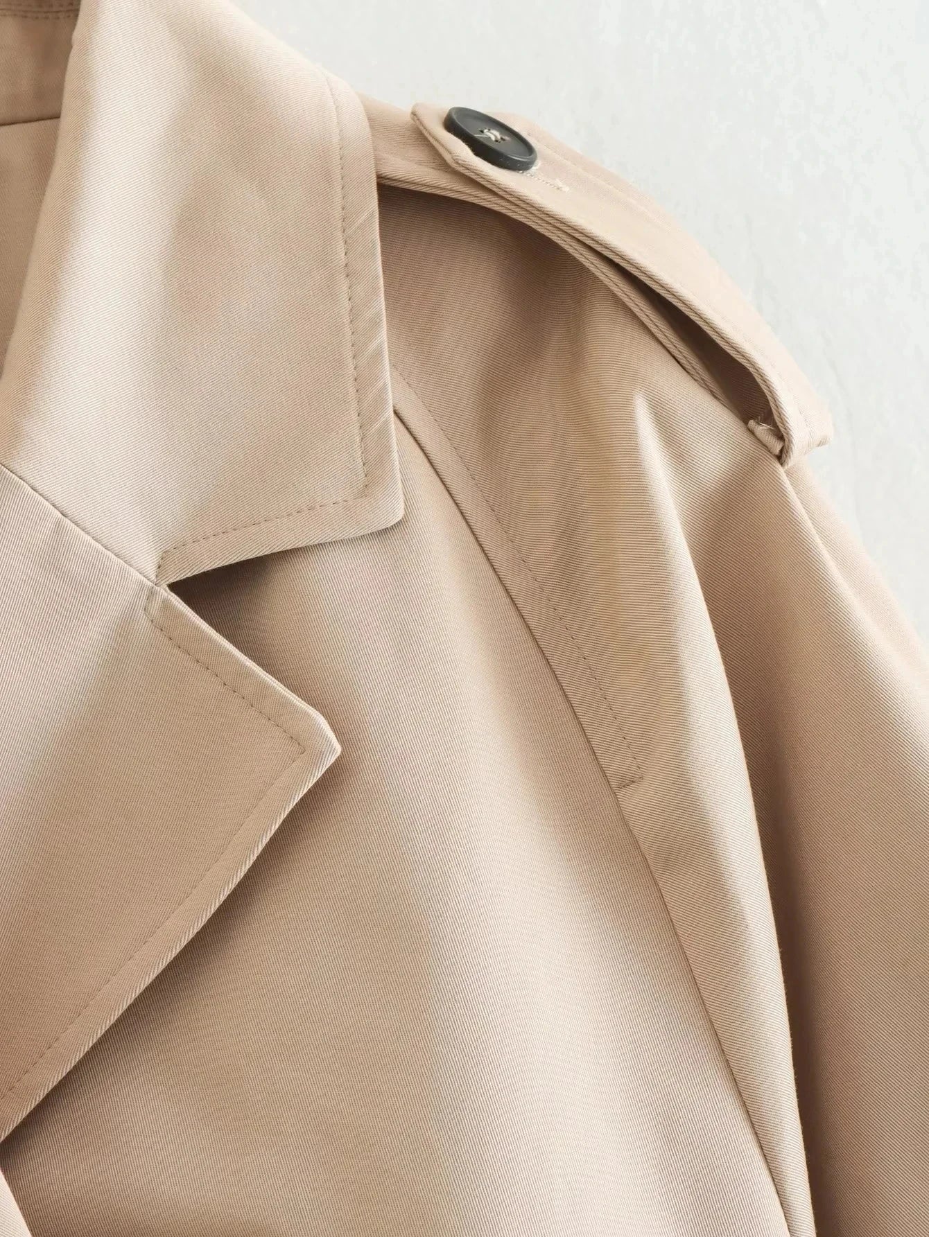 Trench court beige avec ceinture à la taille, look chic et intemporel.
