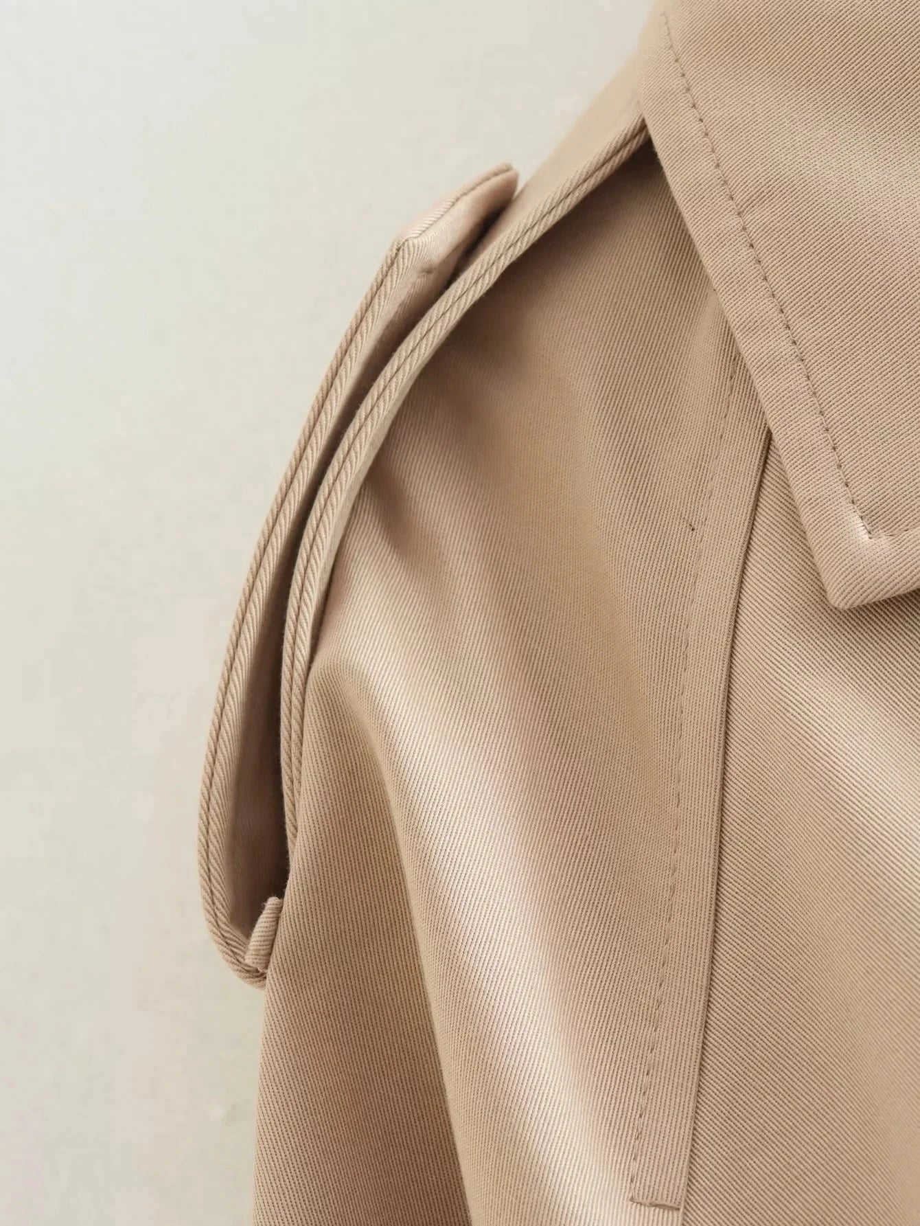 Trench court beige avec ceinture à la taille, look chic et intemporel.
