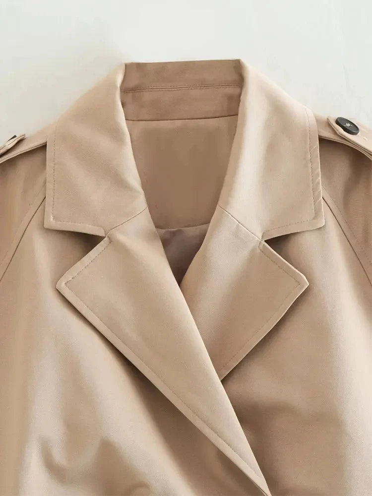 Trench court beige avec ceinture à la taille, look chic et intemporel.