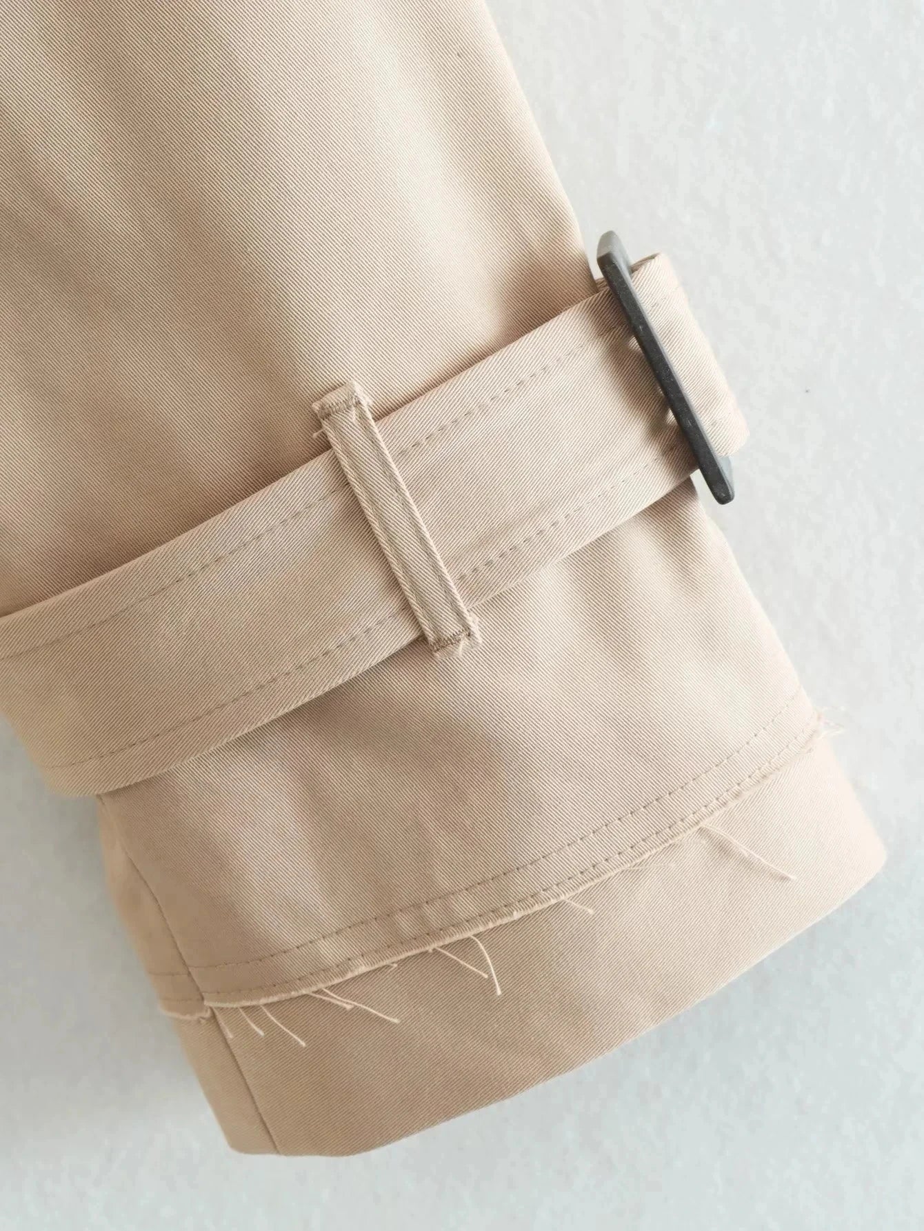 Trench court beige avec ceinture à la taille, look chic et intemporel.